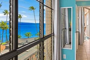 A balcony with a view of the ocean and palm trees.