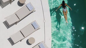 A poolside area with lounge chairs and a person swimming. - Anapollo Boutique Hotel - Adults Only (Naxos)