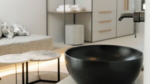A modern kitchen with a black bowl on the counter, a white sofa with patterned cushions, and a minimalist shelving unit in the background. - Anapollo Boutique Hotel - Adults Only (Naxos)