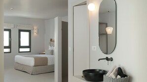 A modern bedroom with a large bed, a bedside table, a mirror, and a wall-mounted light fixture. - Anapollo Boutique Hotel - Adults Only (Naxos)