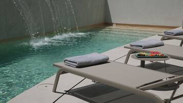 A poolside area with lounge chairs and a small table with towels and fruit.
