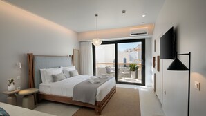 A modern bedroom with a large bed, a TV, and a balcony with outdoor seating. - Anapollo Boutique Hotel - Adults Only (Naxos)