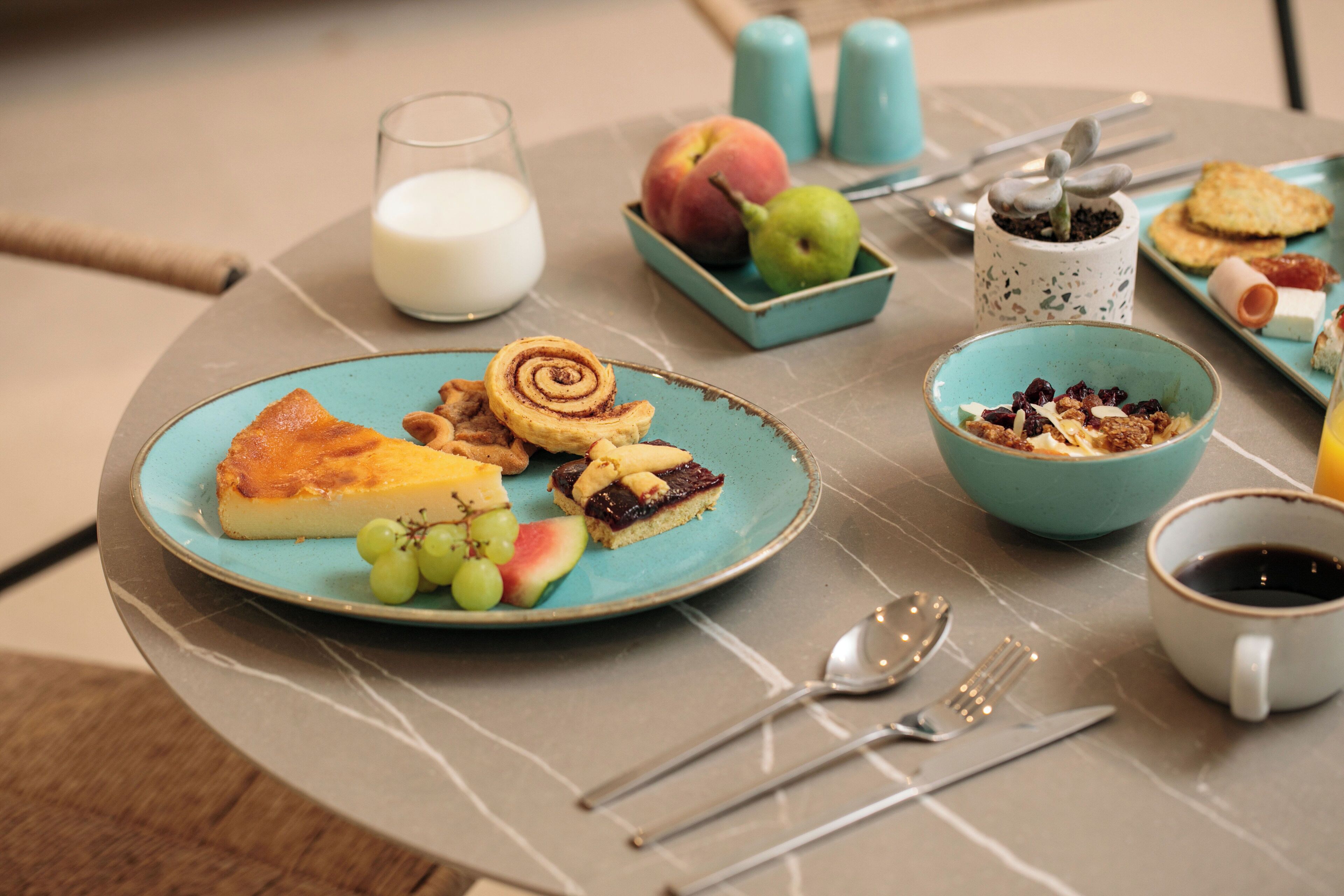 A breakfast setting with a plate of food, a glass of milk, and a bowl of cereal.