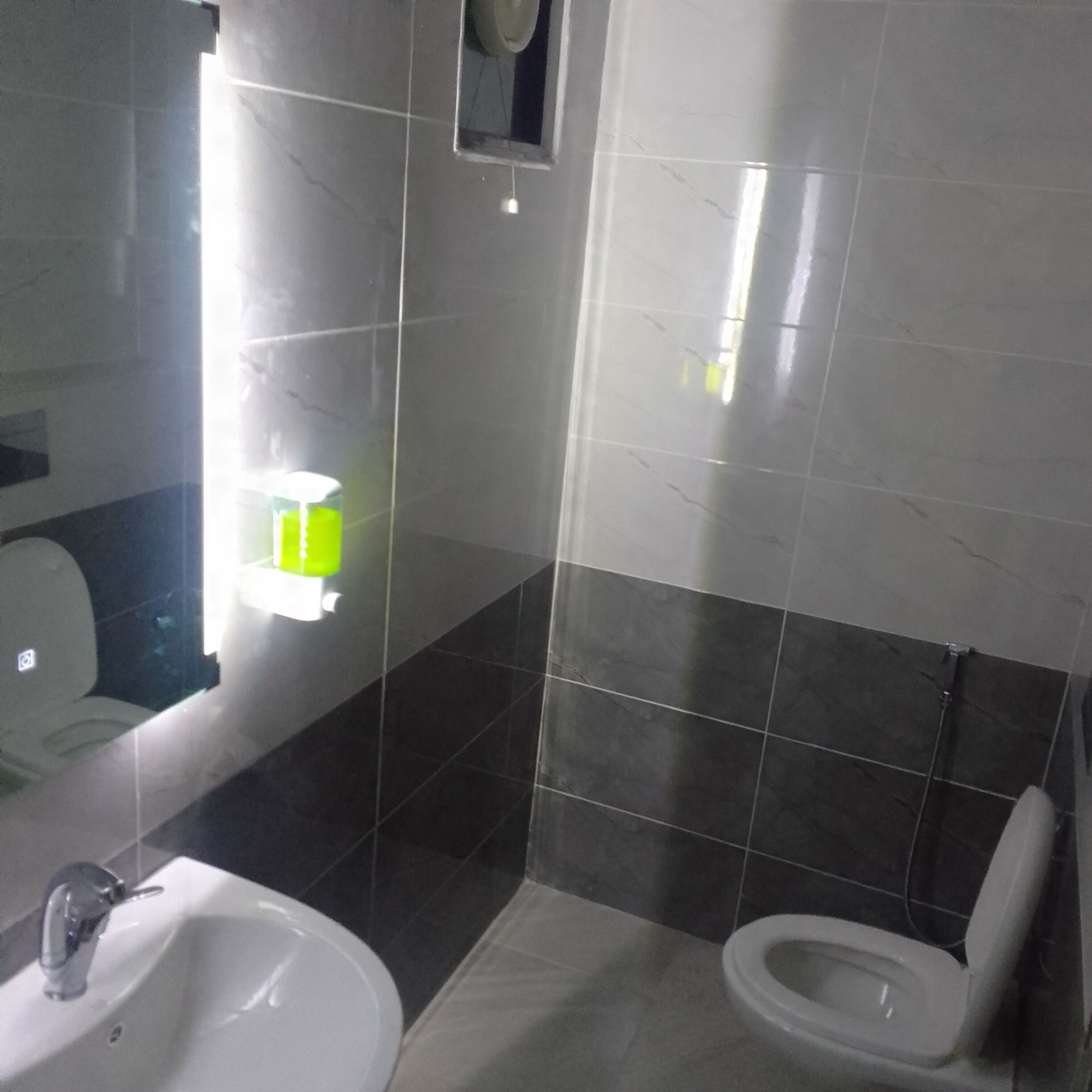 Un baño con lavamanos, inodoro y espejo.