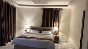 Ein Hotelzimmer mit Bett, Nachttischen, einer Lampe und Vorhängen.