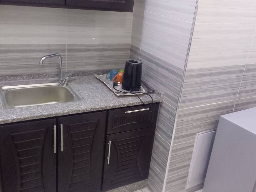 A kitchen with dark cabinets, a granite countertop, a sink, and a small appliance.