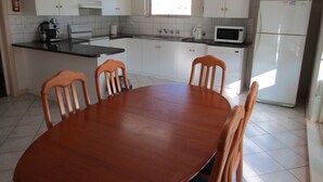 Una cocina con gabinetes blancos, una mesa de comedor de madera y sillas.