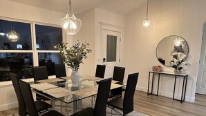 A modern dining room with a glass table, black chairs, and a vase of flowers.