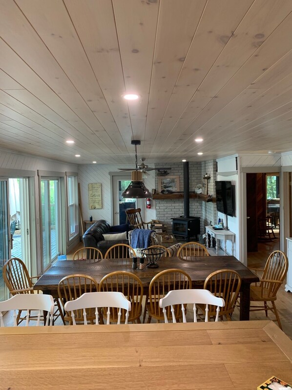 A spacious dining area with a large wooden table and chairs, a ceiling fan, and a brick fireplace.