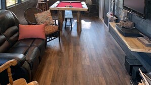 A cozy indoor space with a pool table, leather seating, a mounted deer head, and a television. - Totally private boat access cottage with all amenities (Plevna)