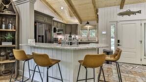 A kitchen with a central island, bar stools, wooden ceiling beams, and a fish decoration.