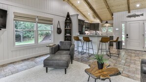 A spacious living room with a grey sofa, a coffee table, and a kitchen in the background.
