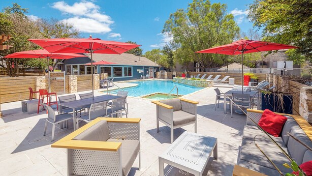 A poolside area with lounge chairs, umbrellas, and a pool. - Cozy BoHo 2bd Apartment | Cedar Park/North Austin (Austin)