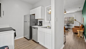 A compact kitchen with white cabinets, a built-in dishwasher, and a coffee maker. - Cozy BoHo 2bd Apartment | Cedar Park/North Austin (Austin)