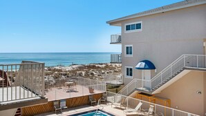 Un hotel frente a la playa con piscina, zona de estar al aire libre y vistas al océano.