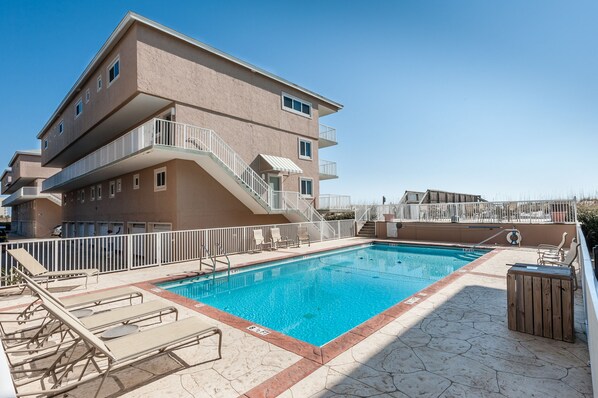 A multi-story building with a swimming pool, outdoor seating, and a staircase leading to the upper floors. - ✨Beach Front Corner Condo-Pool-Garage-2BR Beach Haven in Starboard Village✨ (Pensacola Beach)