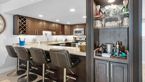 Una cocina moderna con armarios de madera oscura, un refrigerador de acero inoxidable y una zona de bar con taburetes.