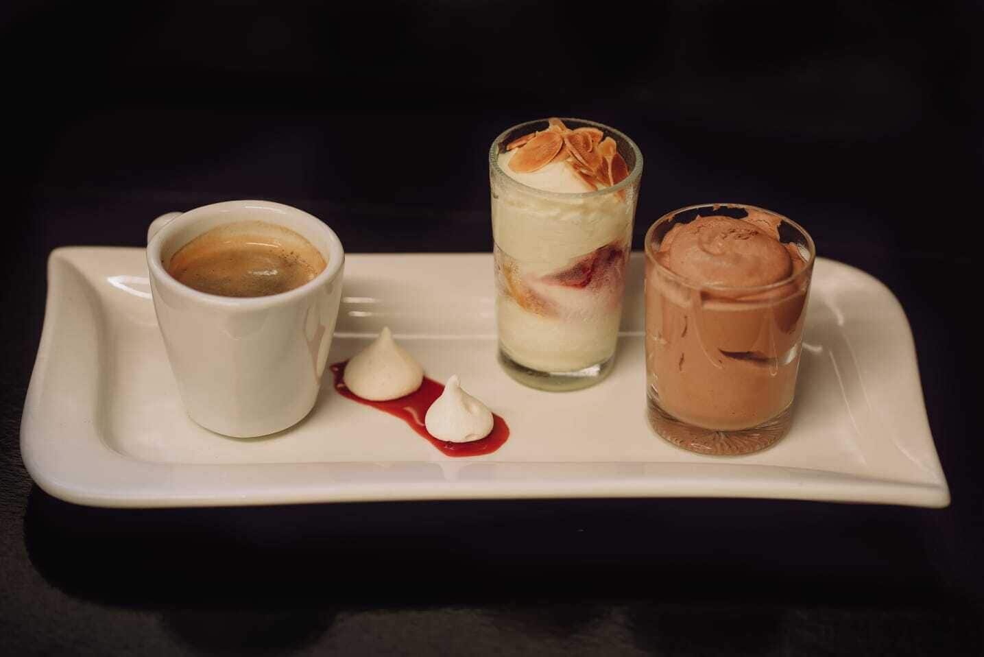 Un plateau de desserts comprenant une tasse de café, un dessert à plusieurs couches et un dessert au chocolat.