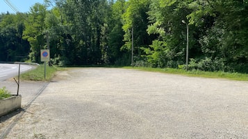 A gravel area with a no parking sign and a road curving to the left.
