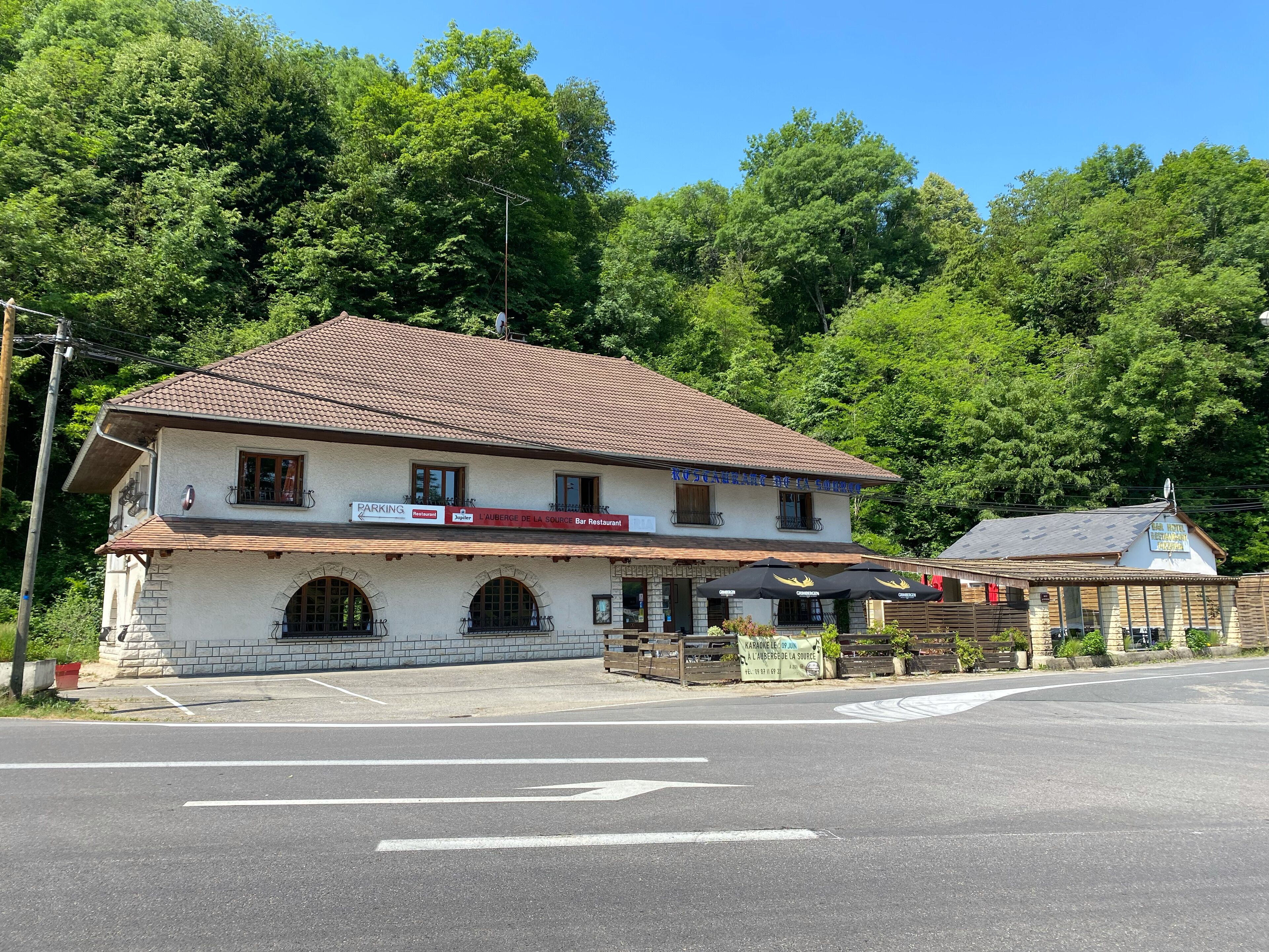 A two-story building with a tiled roof, a sign for a restaurant, and a small annex with a blue roof.