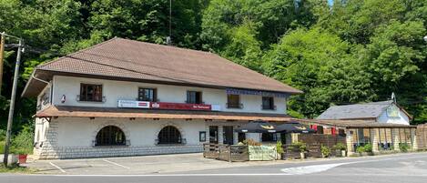 A two-story building with a tiled roof, a sign for a restaurant, and a small annex with a blue roof.