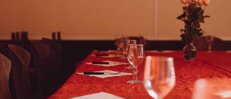 Una larga mesa de comedor con sillas, un florero con flores y copas de vino preparadas para una comida.