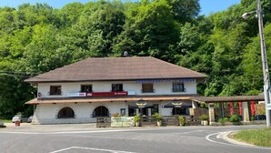 Un bâtiment avec un toit en tuiles, un bar appelé « Lauber de La Source » et des tables à l’extérieur, protégées par des parasols.