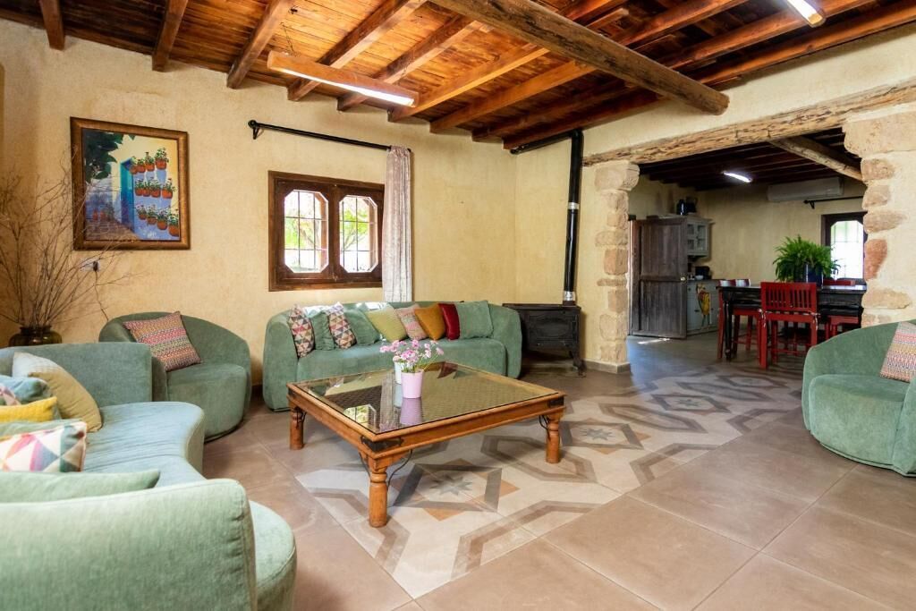 Ein gemütliches Wohnzimmer mit grünen Sofas, einem Holztisch und einem Bild an der Wand.