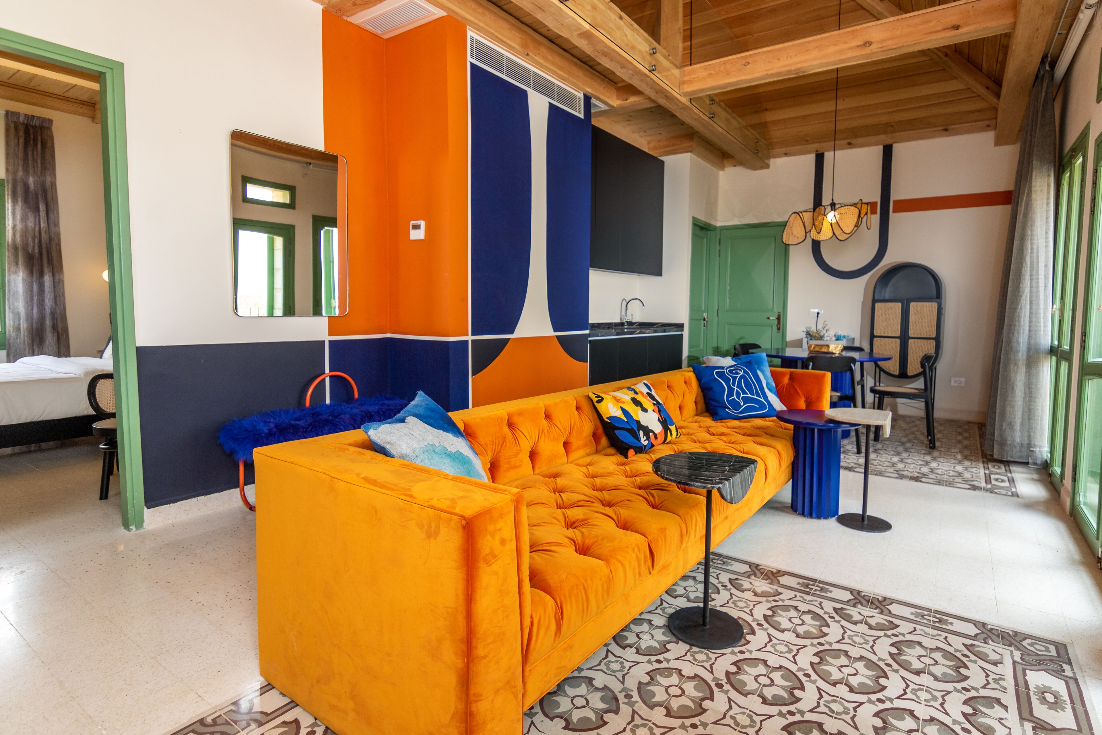 Una sala de estar moderna con un sofá naranja intenso, un tapete estampado y una puerta verde.