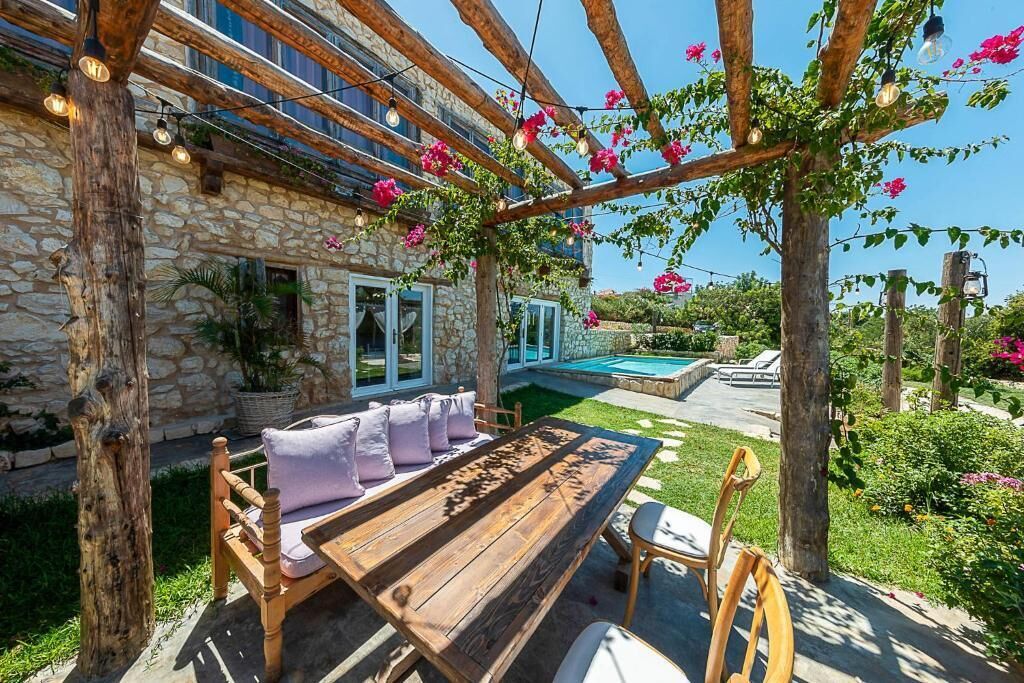 Une table et des chaises en bois sont disposées à l’extérieur, avec un bâtiment en pierre en arri ère-plan.