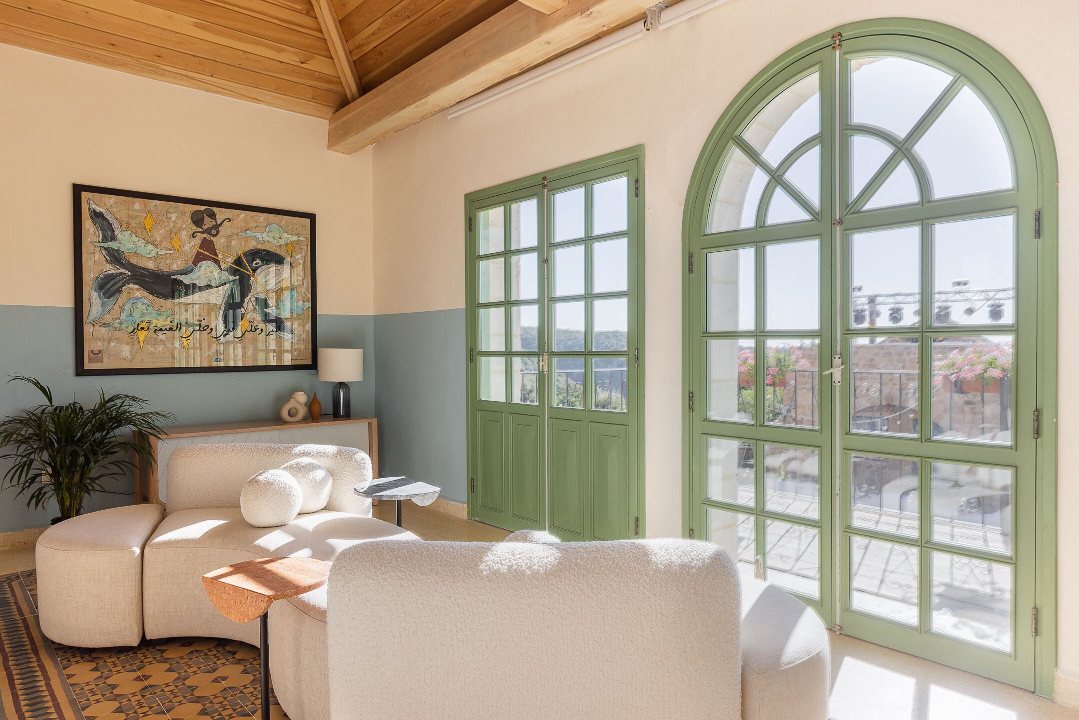 A cozy room with a sofa, a table, and a large arched window offering a view of the city.
