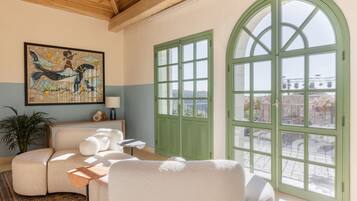 A cozy room with a sofa, a table, and a large arched window offering a view of the city.