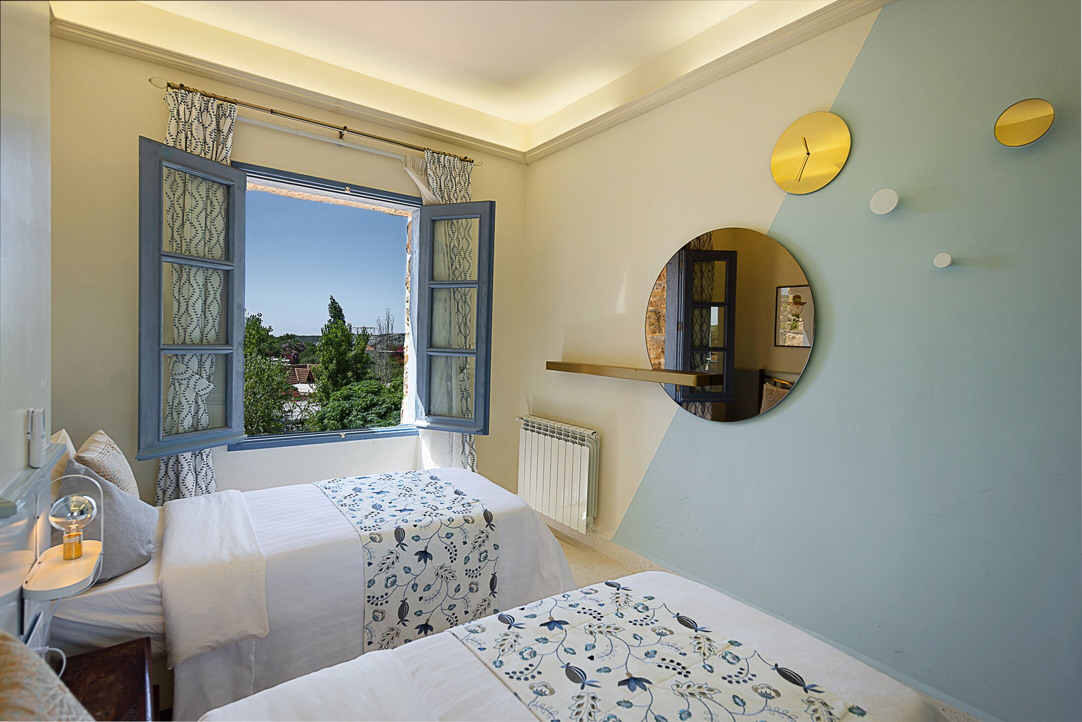 Un dormitorio con dos camas, una ventana con cortinas, un espejo y un reloj en la pared.