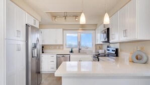 A modern kitchen with white cabinetry, stainless steel appliances, and pendant lighting. - Stunning Home w/Ocean-Mountain Views in East Oahu Serene Family Vacation (Honolulu)