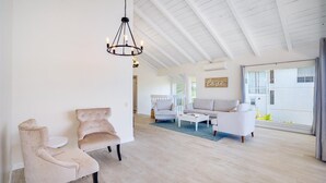 A spacious living room with a high ceiling, a chandelier, and a large window offering a view of the outdoors. - Stunning Home w/Ocean-Mountain Views in East Oahu Serene Family Vacation (Honolulu)