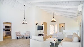 A spacious living room with a kitchen in the background, featuring modern furniture and a high ceiling with exposed beams. - Stunning Home w/Ocean-Mountain Views in East Oahu Serene Family Vacation (Honolulu)