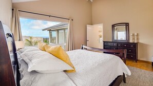 A bedroom with a large bed, a dresser, a mirror, and a view of the beach. - Stunning Home w/Ocean-Mountain Views in East Oahu Serene Family Vacation (Honolulu)