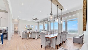 Un salón amplio con piso de madera, una mesa de comedor con sillas de mimbre y un sofá gris.