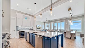 Una cocina moderna con una isla central, electrodomésticos de acero inoxidable e iluminación colgante.