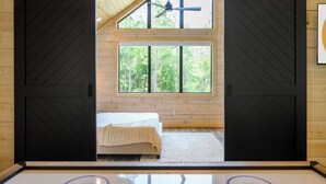 A bedroom with a bed, a large window, and a ceiling fan.