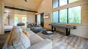 A cozy cabin interior with a sofa, bean bag, and a pool table.