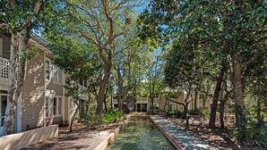 A serene courtyard with a clear water feature, surrounded by trees and buildings. - Great Second Cottage at Hidden Dunes (Miramar Beach)