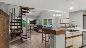 A spacious kitchen with a central island, a dining area with a large table, and a living room with a sofa and chairs. - Great Second Cottage at Hidden Dunes (Miramar Beach)