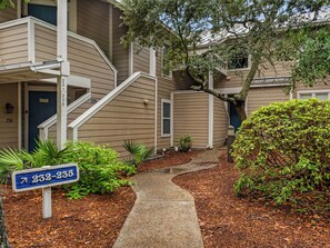 A multi-story residential building with a front entrance, a staircase, and a pathway leading to the entrance. - Great Second Cottage at Hidden Dunes (Miramar Beach)