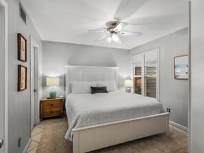 A bedroom with a bed, bedside lamps, a ceiling fan, a wooden nightstand, and a closet with a sliding door. - Great Second Cottage at Hidden Dunes (Miramar Beach)