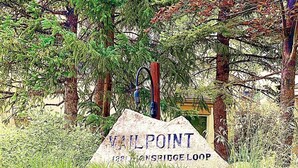 Un panneau indiquant « VAIL POINT » et « 1221 LIONSBRIDGE LOOP », entouré de rochers et de verdure.