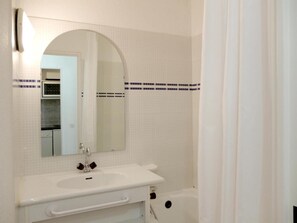 Bathroom features a large mirror, sink, cabinet, and bathtub.