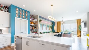 Cocina moderna con armarios blancos, una isla central y vistas a la ciudad a través de amplios ventanales.