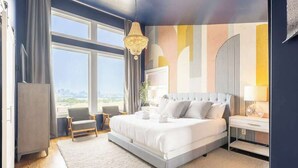 Habitación de hotel moderna con una cama grande, un área de descanso y vistas a la ciudad.