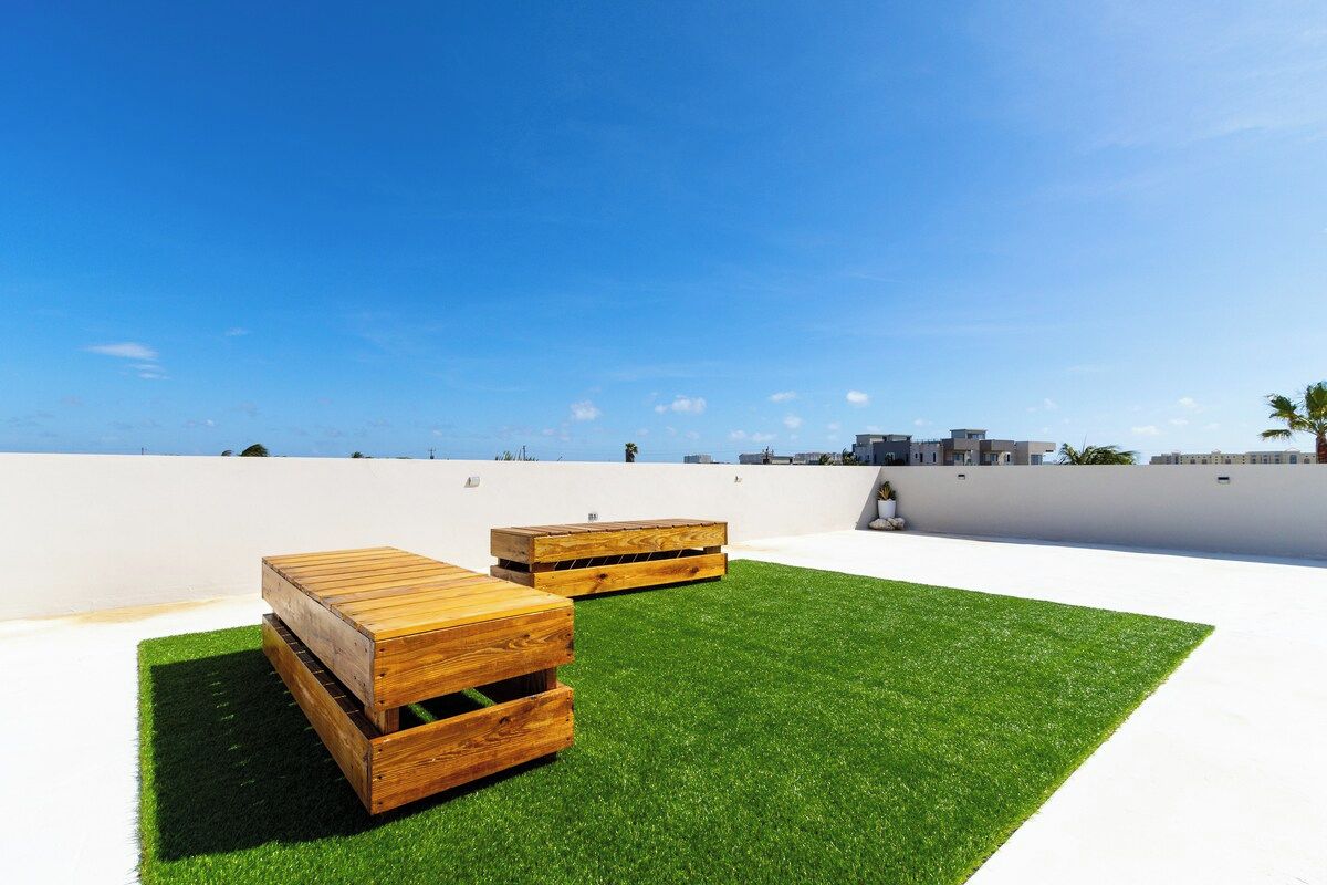 A rooftop terrace with artificial grass and wooden furniture.